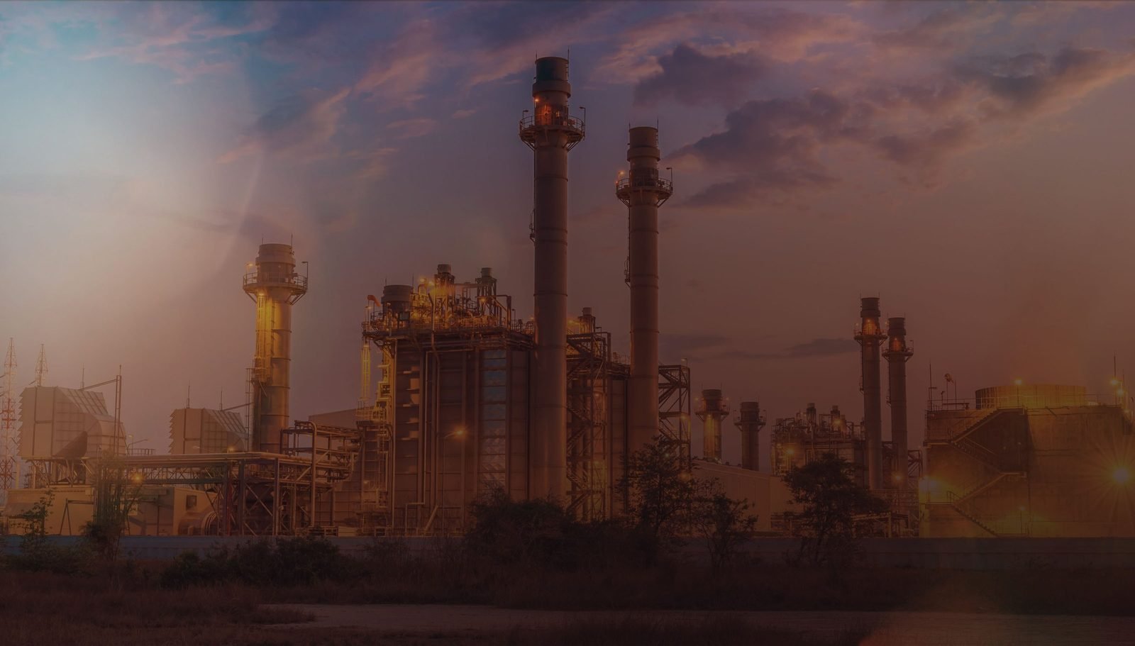 Planta industrial com chaminés ao entardecer